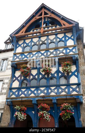 Fachwerkhaus Fenster mit hängenden Blumentöpfen dekoriert. Bretagne, Frankreich. Erhaltung und Restaurierung alter Gebäude, europäisches Denkmalkonzept Stockfoto