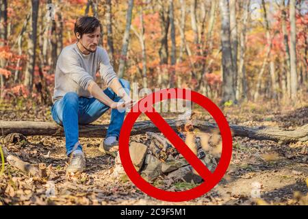 Verboten, ein Feuer zu machen. Mann wärmt seine Hände durch ein Feuer. Arme Männer warm draußen in der Nähe Rauchen Barre Stockfoto