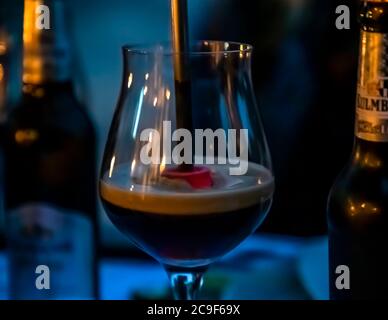 Ein glühendes Rührhölz wird dampfend in ein Glas dunklen Eisbock-Bieres getaucht, sein Schaumkopf wird karamellbraun, für das heiße Finale des Bierseminars auf den Hollerhöfen in Kemnath-Waldeck, Oberpfalz, Bayern, Deutschland. In dieser Tradition, bekannt als „Bierstacheln“, erhitzt ein rotglühendes Rührhölz das Bier, karamellisiert seinen Restzucker und lässt es schäumen. Stockfoto