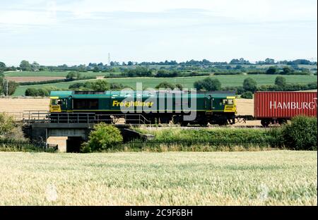 Diesel-Lokomotive der Baureihe 66 Nr. 66592 'Johnson Stevens Agencies', die einen freightliner-Zug auf der West Coast Main Line, Northamptonshire, UK, zieht Stockfoto