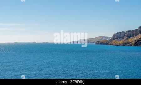 Felsformationen in dramatischen Klippen an der Jurassic Coast in Brandy Bay, Kimmeridge, Dorset, Großbritannien. In der Ferne befinden sich ungenutzte Kreuzfahrtschiffe in Weymouth Bay Stockfoto