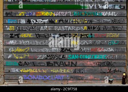 ‘All Cops are Bastards’ / ACAB - eindeutiger Anti-Polizei-Slogan auf Englisch unter den italienischen Spraydose Graffiti defacing ein Metall Rollladen Garagentor in Via del Fosso, Lucca, Toskana, Italien. Stockfoto