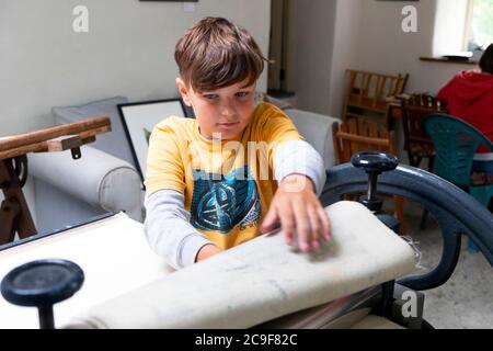 Junge mit einer Littlejohn Radierpresse während des Lernens Druckgrafik in einem Art Class Workshop Studio in Carmarthenshire Wales UK KATHY DEWITT Stockfoto