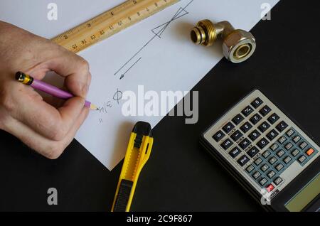 Eine männliche Hand zeichnet ein Diagramm von zu Hause Sanitär. Klempner macht die Berechnungen. Kaukasischer Mann mittleren Alters. Sanitär. Stockfoto