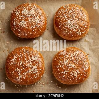 Gebackene Sesambrötchen auf braunem Pergamentpapier, Zutat für einen Hamburger, Draufsicht Stockfoto