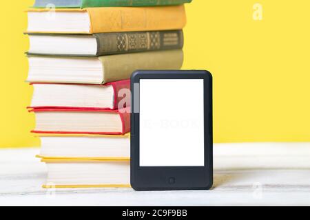 Lesen. E-Book-Reader und ein Stapel Bücher auf gelbem Hintergrund. Modell. Konzept der Bildung und elektronische Geräte. Stockfoto