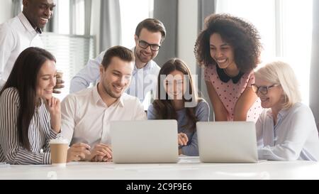 Lächelnd und freundlich – die Mitarbeiter nutzen den Laptop und sehen sich gemeinsam das Webinar an Stockfoto