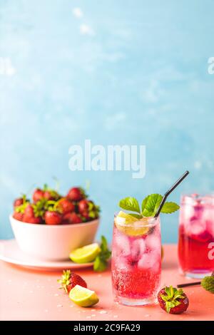 Erdbeer Mojito Cocktail mit Eis in zwei Gläsern mit Wassertropfen auf hellblauem Hintergrund, rosa Tafel. Platz kopieren, Sommerurlaub und Party Stockfoto