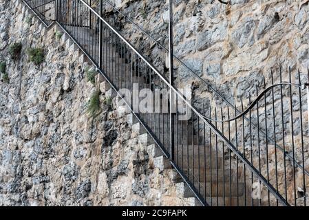 Architektonisches Detail der Steinblockwand mit privater Treppe mit Eisengeländer und Zaun, die von der Strandpromenade in Estoril, Por Stockfoto