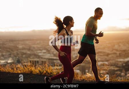 Sportler laufen früh am Morgen auf der Straße. Fitness Mann und Frau sprinten auf der Straße. Stockfoto