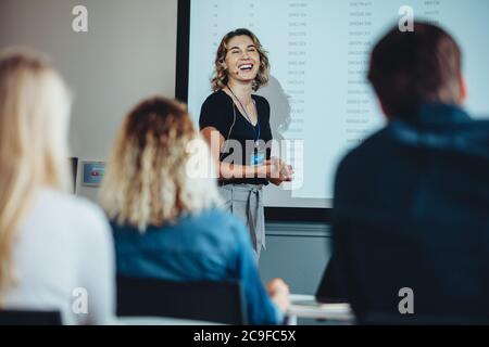 Geschäftsfrau, die an der Projektorleinwand steht und während einer Präsentation lächelt. Erfolgreiche Unternehmerin hält eine Rede auf der Konferenz. Stockfoto