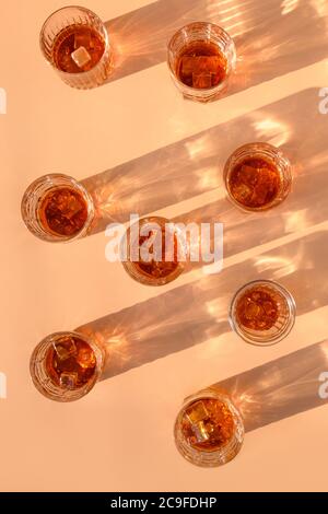 Viele Gläser kalten Whiskys serviert in Felsen mit Rosmarin auf beige trendigen Hintergrund. Vertikales Format. Stockfoto