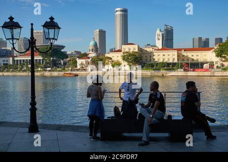 Menschen entspannen am Singapore River, am Boat Quay, Singapur; b/g: Empress Place (ctr & r), die Kuppel der Nationalgalerie (ctr l) Stockfoto