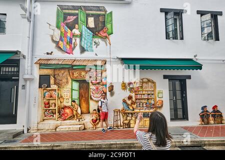 Ein touristisches Paar, das vor einem umfangreichen Wandgemälde des Künstlers Yip Yew Chong fotografiert; Mohamed Ali Lane, Chinatown, Singapur Stockfoto