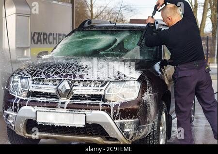 Ein Mann wäscht ein Auto bei einer berührungslosen Autowäsche, ein Mann wäscht ein braunes Auto, Kaliningrad, Russland, 1. März 2020 Stockfoto