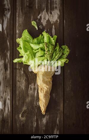 Frischer Salat leaveson in einem Papierbeutel ein dunkler Holztisch. Batavia-Salat Stockfoto