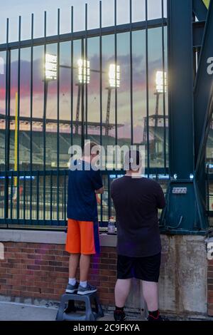 Detroit, Michigan, USA. Juli 2020. Baseball-Fans beobachten die Detroit Tigers spielen die Kansas City Royals durch einen Zaun im Comerica Park. Zuschauern ist es aufgrund der Coronavirus-Pandemie untersagt, das Stadion zu betreten. Kredit: Jim West/Alamy Live Nachrichten Stockfoto