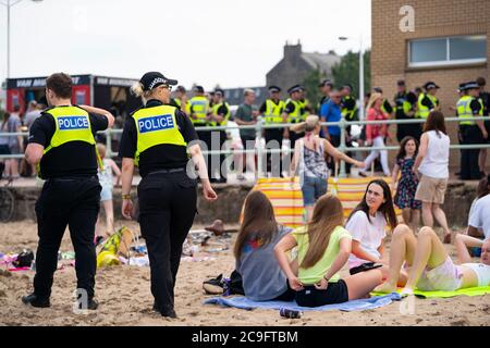 Edinburgh, Schottland, Großbritannien. 31. Juli 2020. Temperatur von 25C und Sonnenschein brachten riesige Menschenmassen nach Portobello Beach außerhalb von Edinburgh. Mehrere große Gruppen von Teenagern genossen den Strand und alkoholische Getränke waren sehr beliebt. Um ca. 15 Uhr brach ein Ärger zwischen jungen Leuten am Strand aus und Polizeiverstärkungen waren schnell vor Ort und mehrere Leute wurden festgenommen. Westbank Street war für den Verkehr gesperrt und ca. 30 Polizisten patrouillieren die Promenade. Die Polizei beschlagnahmt Alkohol von den Teenagern, die am Strand bleiben. Iain Masterton/Alamy Live News Stockfoto