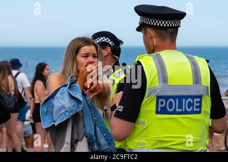 Edinburgh, Schottland, Großbritannien. 31. Juli 2020. Temperatur von 25C und Sonnenschein brachten riesige Menschenmassen nach Portobello Beach außerhalb von Edinburgh. Mehrere große Gruppen von Teenagern genossen den Strand und alkoholische Getränke waren sehr beliebt. Um ca. 15 Uhr brach ein Ärger zwischen jungen Leuten am Strand aus und Polizeiverstärkungen waren schnell vor Ort und mehrere Leute wurden festgenommen. Westbank Street war für den Verkehr gesperrt und ca. 30 Polizisten patrouillieren die Promenade. Die Polizei beschlagnahmt Alkohol von den Teenagern, die am Strand bleiben. Iain Masterton/Alamy Live News Stockfoto