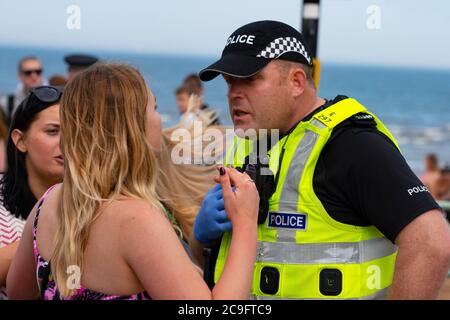 Edinburgh, Schottland, Großbritannien. 31. Juli 2020. Temperatur von 25C und Sonnenschein brachten riesige Menschenmassen nach Portobello Beach außerhalb von Edinburgh. Mehrere große Gruppen von Teenagern genossen den Strand und alkoholische Getränke waren sehr beliebt. Um ca. 15 Uhr brach ein Ärger zwischen jungen Leuten am Strand aus und Polizeiverstärkungen waren schnell vor Ort und mehrere Leute wurden festgenommen. Westbank Street war für den Verkehr gesperrt und ca. 30 Polizisten patrouillieren die Promenade. Die Polizei beschlagnahmt Alkohol von den Teenagern, die am Strand bleiben. Iain Masterton/Alamy Live News Stockfoto