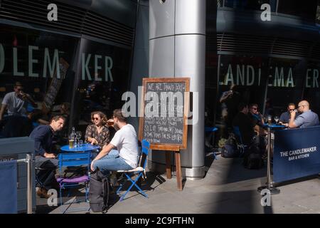 Stadtarbeiter trinken vor einer Bar in der Cannon Street, die am Programm der Regierung "Eat Out to Help Out" teilnimmt, einer Initiative für die Lebensmittel- und Getränkeindustrie, die während der Coronavirus-Pandemie am 30. Juli 2020 in London, England, zur Ankurbelung der Wirtschaft beitragen soll. Stockfoto