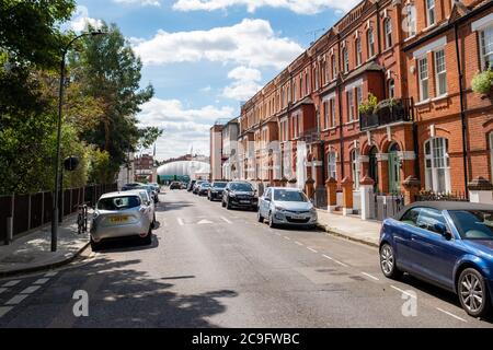 Straße mit attraktiven Häusern an der U-Bahn-Station Barons Court und dem Queens Club Tennisclub am Ende der Straße Stockfoto