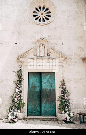 Die Türen zur Kirche sind grün mit Mustern, geschmückt mit Blumen und göttlichen Symbolen. Insel Gospa od Skrpella in Perast, Montenegro. Stockfoto
