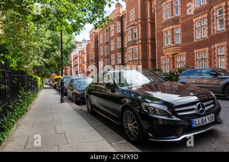 LONDON - JULI 2020: Schwarzer Mercedes-Wagen auf der schönen Straße der Kensington Stadthäuser geparkt Stockfoto