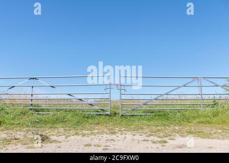 Galvanisierter Stahl Bauernhof Tor über Eingang zum Weizenfeld in der Sommersonne, aber geschlossen mit Polyester-Seil Knoten. Zugriff auf Metaphern verweigert, Barriere, Eintritt verboten. Stockfoto