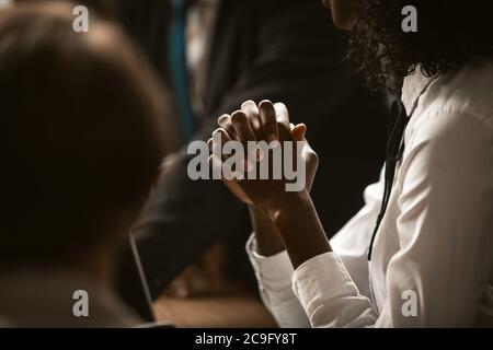 afroamerikanische Geschäftsfrau faltete die Hände, um für Geschäft zu beten. Dunkelhäutige junge Frau faltete die Hände zusammen anmutige Hände im Vordergrund. Getönt Stockfoto