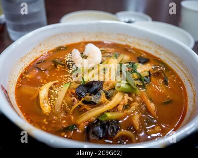 Jjamppong, koreanische Nudelsuppe mit roter, würziger, auf Meeresfrüchten basierender Brühe, gewürzt mit Chilipulver. Chinesisches Essen im koreanischen Stil. Stockfoto