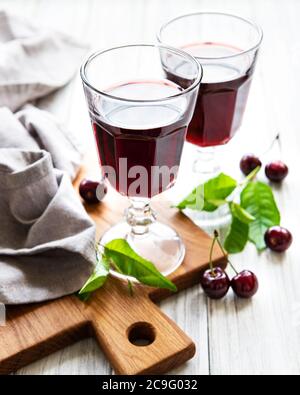 Kirschlikör im Glas und frisches Obst auf einem Holztisch Stockfoto