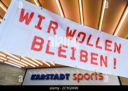 30. Juli 2020, Berlin, Berlin, Deutschland: Ein Protestschild mit der Aufschrift "Wir wollen bleiben" ist am Eingang eines Karstadt Sport Stores in Berlin-Charlottenburg zu sehen. Die Warenhausgruppe Galeria Karstadt Kaufhof GmbH hatte sich aufgrund der koronabedingten Schließung aller Filialen während der weltweiten Covid-19-Pandemie in Schwierigkeiten gebracht. Mitte Juni kündigte das Unternehmen die Schließung von 62 seiner 172 Kaufhäuser im Rahmen der Restrukturierungspläne an, die meisten davon befinden sich im Land Berlin. Inzwischen ist die Zahl landesweit auf 50 gesunken. (Bild: © Jan Scheunert/ZUMA Wire) Stockfoto