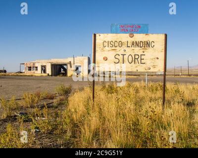 Eine alte Namenstafel für den Laden mit einer Ruine im Hintergrund in der Geisterstadt Cisco Landing, einer alten Bahnhofsstadt in Utah, USA Stockfoto