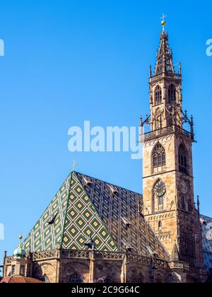 Der Dom von Bozen ist eine restaurierte spätgotische Kirche mit einem gemusterten, mehrfarbigen Marmordach und einem kunstvollen Turm Stockfoto