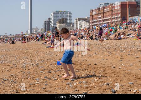 Ein kleiner Junge geht über Kiesel heißesten Tag des Jahres auf Brighton Beach Stockfoto