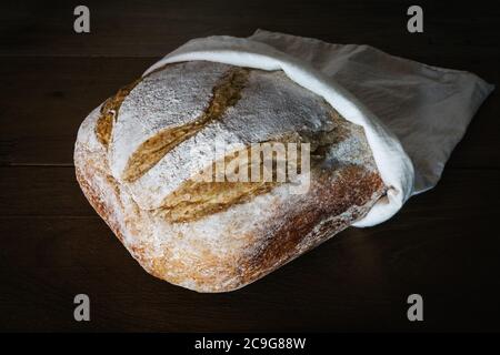 Knusprige handwerkliche Brot in Leinenbeutel über rustikalen Holzhintergrund. Brot mit Fruchthefe Wasser gemacht. Natürliche Gärung Stockfoto