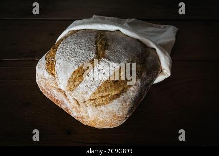 Knusprige handwerkliche Brot in Leinenbeutel über rustikalen Holzhintergrund. Brot mit Fruchthefe Wasser gemacht. Natürliche Gärung Stockfoto