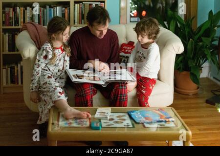 Vater liest seinen Kindern zu weihnachten eine Gute-Nacht-Geschichte Stockfoto