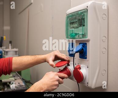 Nahaufnahme einer männlichen Hand, die sich in eine elektrische einsteckt Schalterplatine Stockfoto