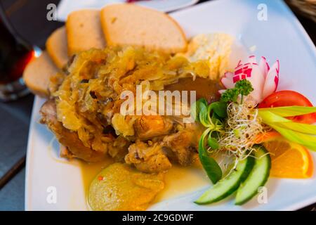 Appetitlich Schweinshaxe gebacken in Bier und Sauerkraut mit Soße und Weißbrot serviert. Stockfoto