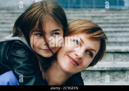 Huckepack Fahrt mit Mama. Mutter und Tochter umarmen sich und lächeln. Stockfoto