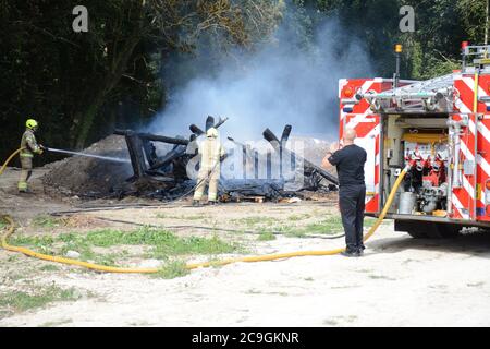 31. Juli 2020 - ein altes Lagerfeuer brennt auf Ackerland in Newchapel bei Lingfield in Surrey. Ein einziges Feuergerät nimmt in weniger als 11 Minuten vom East Grinstead ab und erhält die Kontrolle, um die Ausbreitung auf nahe gelegene Wälder zu verhindern. Die übermäßige Hitze von 32C, starkes Sonnenlicht und starke Brise waren alle Faktoren, die zu seiner Selbstverbrennung und seine Neigung, zu versuchen, Feuer in den Wald zu setzen. Stockfoto