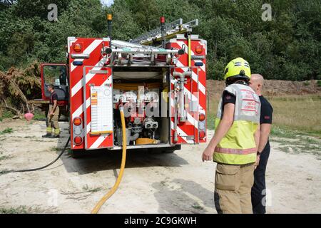 31. Juli 2020 - ein altes Lagerfeuer brennt auf Ackerland in Newchapel bei Lingfield in Surrey. Ein einziges Feuergerät nimmt in weniger als 11 Minuten vom East Grinstead ab und erhält die Kontrolle, um die Ausbreitung auf nahe gelegene Wälder zu verhindern. Die übermäßige Hitze von 32C, starkes Sonnenlicht und starke Brise waren alle Faktoren, die zu seiner Selbstverbrennung und seine Neigung, zu versuchen, Feuer in den Wald zu setzen. Stockfoto