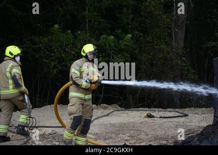 31. Juli 2020 - ein altes Lagerfeuer brennt auf Ackerland in Newchapel bei Lingfield in Surrey. Ein einziges Feuergerät nimmt in weniger als 11 Minuten vom East Grinstead ab und erhält die Kontrolle, um die Ausbreitung auf nahe gelegene Wälder zu verhindern. Die übermäßige Hitze von 32C, starkes Sonnenlicht und starke Brise waren alle Faktoren, die zu seiner Selbstverbrennung und seine Neigung, zu versuchen, Feuer in den Wald zu setzen. Stockfoto