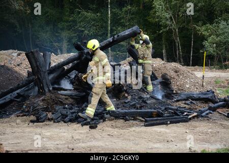 31. Juli 2020 - ein altes Lagerfeuer brennt auf Ackerland in Newchapel bei Lingfield in Surrey. Ein einziges Feuergerät nimmt in weniger als 11 Minuten vom East Grinstead ab und erhält die Kontrolle, um die Ausbreitung auf nahe gelegene Wälder zu verhindern. Die übermäßige Hitze von 32C, starkes Sonnenlicht und starke Brise waren alle Faktoren, die zu seiner Selbstverbrennung und seine Neigung, zu versuchen, Feuer in den Wald zu setzen. Stockfoto