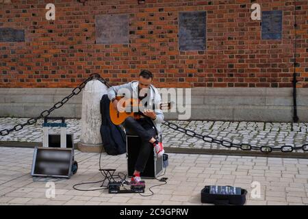 Krakau, Polen - 12. Juli 2020: Ein männlicher Straßenkünstler, der im Stadtzentrum akustische Gitarre spielt Stockfoto