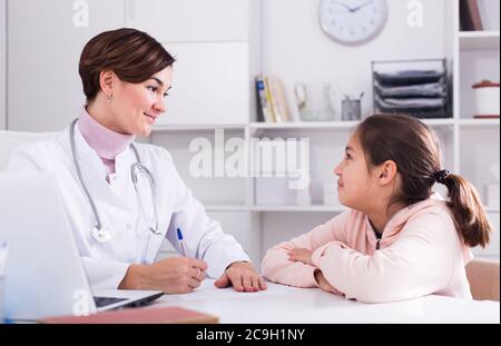 Arzt füllt die Karte des Patienten für Mädchen und fragt sie über Gesundheit in der Arztpraxis Stockfoto