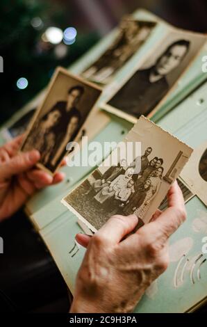 Weibliche Hände halten und altes Foto von ihren Verwandten. Vintage Fotoalbum mit Fotos. Familie und Leben Werte Konzept. Stockfoto