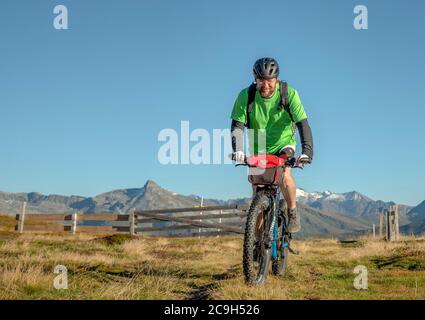 Mountainbiker in den späten Vierzigern fährt mit dem eBike auf einem alpinen Weg gegen blauen Himmel, Bergeralm Freizeitarena, Bikepark, Gries am Brenner Stockfoto